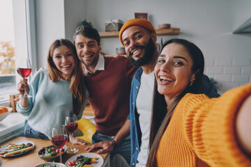 Group of beautiful people making selfie and smiling while enjoying dinner at home together