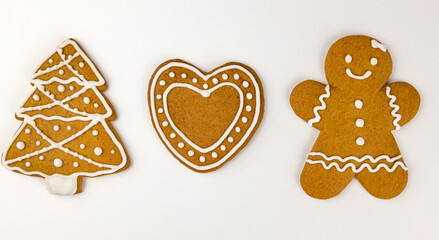Gingerbread woman. Christmas gingerbread cookies with frosting in the shape of a tree, a person and a heart on a white background.