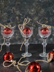 Crystal glasses with red retro Christmas balls on a black rustic table. Creative Christmas composition.