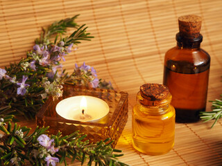 Composition with transparent aromatherapy bottles, candles and rosemary