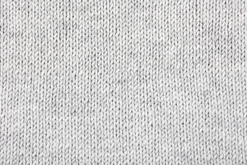 Knitted gray background. Large knitted fabric with a pattern. Close-up of a knitted blanket....