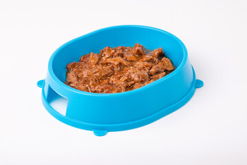 Wet food for cats and dogs in a blue bowl on a white background.