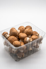 Brown champignons fresh mushrooms in plastic packaging isolated on white background.