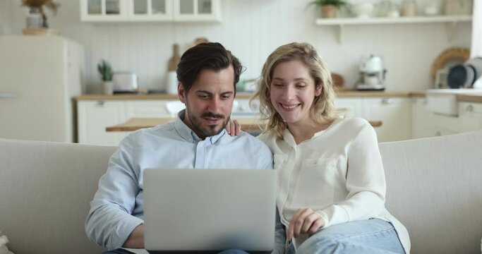 Beautiful 30s couple screaming with joy celebrate on-line lottery, betting, jackpot victory feel happy sit on sofa with laptop. Great news, get huge discounts or commercial offer. Promotion, win, luck