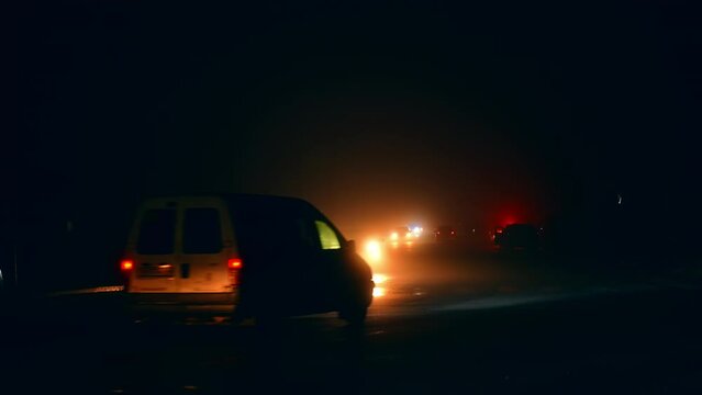 Car road with not working traffic lights at night time. Vehicles driving slowly by the city in blackout.