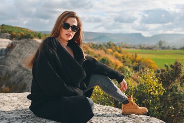 
A white tourist in a gray sweatshirt walks in nature. Beautiful girl in sunglasses. Beautiful view.