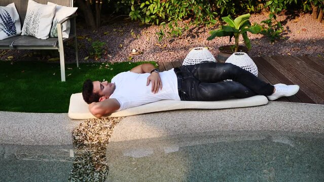 Handsome young man relaxing by swimming pool