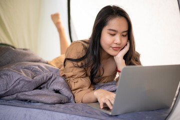 Young Asian woman using computer laptop while vacation in the tent at summer time