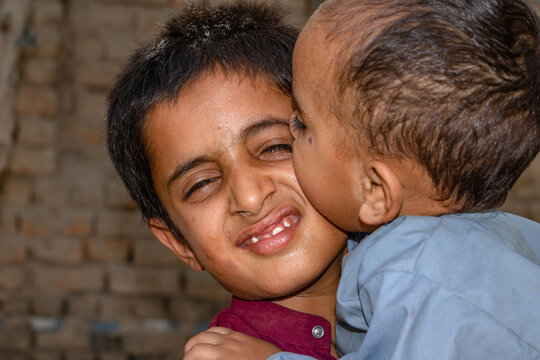 a young boy is carrying his little brother and smiling 