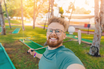 Happy player golfer man making selfie background mini golf in summer park