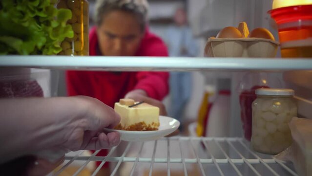 Young African-American woman try to take cake from fridge. Female on diet want to eat pasrty. Realtime