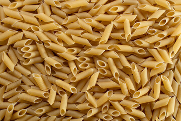 Top view of dry uncooked tortiglioni or rigatoni pasta as a background. Flat lay.