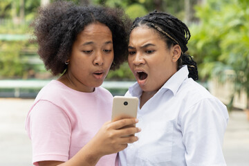 Disappointed African woman using smartphone, concept image of bad news, fake news