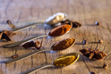 Almonds, cinnamon, paprika and turmeric powder in a spoon on a rustic wooden table.