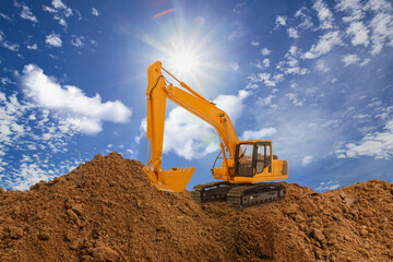 Crawler excavator with Bucket lift up are digging soil in the construction site on the blue sky and sunbeam background