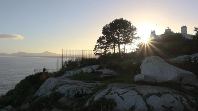 View of Irish coastline in Dalkey near Dublin bay during sunset with boulders and mountains on the background