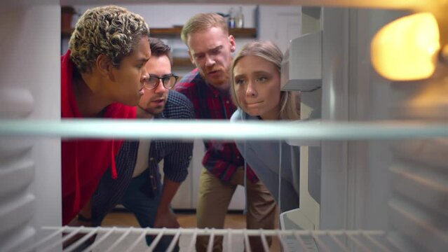 Hungry multiethnic friends open empty fridge. Realtime