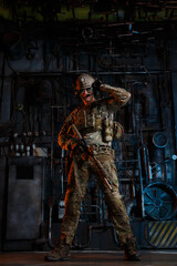Fototapeta na wymiar American soldier in camouflage uniform with a machine gun in his hands on an industrial background.