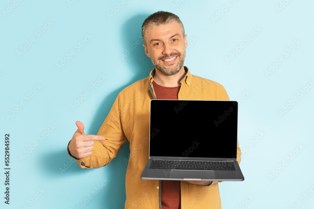 Poster happy mature caucasian man showing laptop computer empty screen, recommending website, mockup
