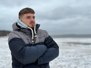 Portrait of serious sad upset young man at winter cold day at beach, walking