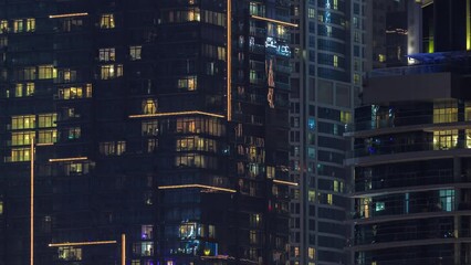 Night view of lights in panoramic windows of multistory buildings aerial timelapse. Illuminated skyscraper with glass furface in a big city - Powered by Adobe