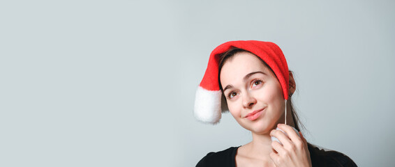 Portrait of beautiful 30 year female model in Santa Claus hat. Dreaming girl. Delight or happiness emotion. Wish list or dreams. New Year spirit. Thoughts of young happy woman. Looks up. Festive mood