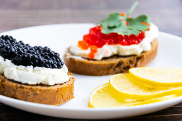 Open sandwiches with red and black caviar on a wooden board. Close-up shooting.