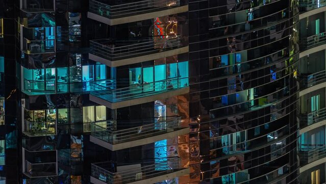 Night view of many glowing windows in apartment residential tower timelapse. High rise skyscraper with lights in rooms and panoramic balconies