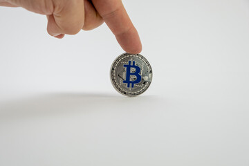 Finger holding one coin of Bitcoin - BTC on the top, isolated on a white background. Copy space.