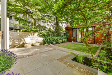 a backyard with trees, plants and patio furniture in the fore - image is from real estate agent's...