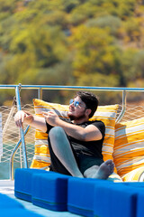 Young man in sunglasses traveling on yacht pointing with hands while telling a funny story to his friend.