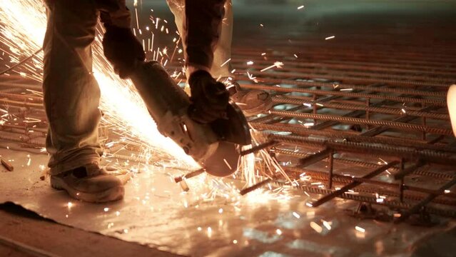 Industrial professional worker is cutting metal rebar with a circular saw. Construction of a factory, hangar