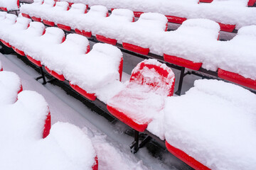Empty outdoor football soccer stadium seats covered with snow in winter