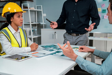 Engineers and competent employer discussing plans and blueprints together with tablet in the...