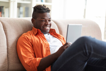 Portrait of happy african man using digital tablet at home - obrazy, fototapety, plakaty