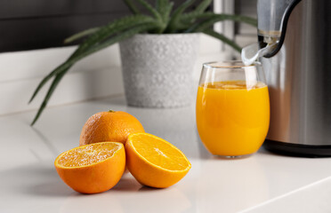 freshly squeezed orange juice, oranges cut in half on top of a kitchen marble, juice squeezer