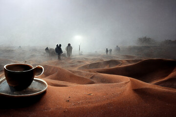 Dark Coffee in the Middle of Sahara desert with people in the Horizon in a foggy weather, in dark yellow and white colors. 