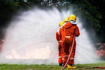 Firefighter Concept. Fireman using water and extinguisher to fighting with fire flame. firefighters fighting a fire with a hose and water during a firefighting training exercise