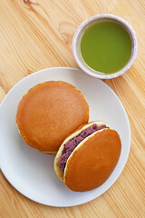 Plate of Delectable Dorayaki with a Cup of Hot Matcha Green Tea Served on Wooden Table