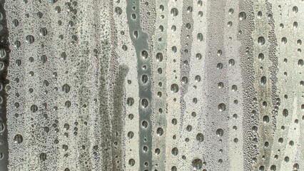 Raindrops fall on the window close-up. Rain, rainy, depressive, dreary weather. Wet drop water. Splashes of water with large drops on the glass. On window with water drops and splashes of water.