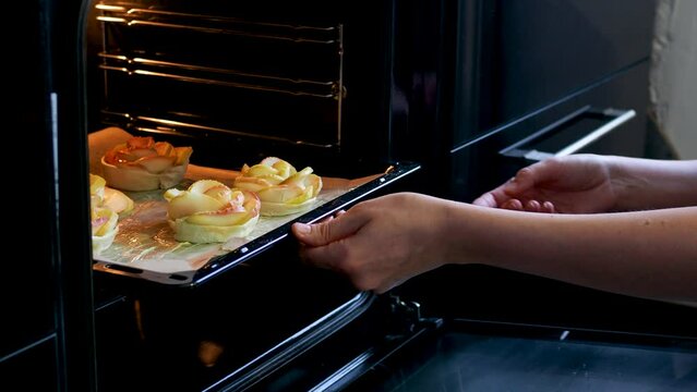 The process of making dessert with apples , homemade cakes . Put a baking sheet with apple buns in the oven