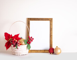 Christmas New Year mock up frame, basket with toy balls, fir tree branch, poinsettia and berries for decoration. Space for text. Seasons greetings template.