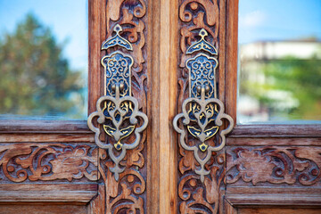 Close-up view of the door with carved beautiful metal handles. 