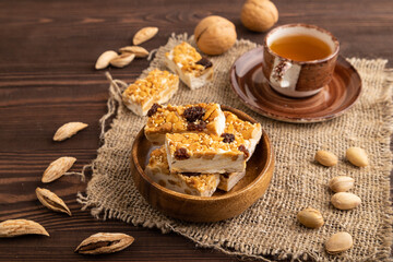Fototapeta na wymiar Traditional candy nougat with nuts and sesame on brown wooden, side view.