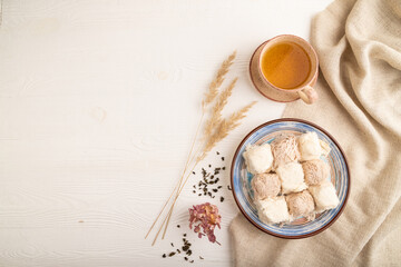 traditional arabic sweets pishmanie and a cup of green tea on white wooden,  top view, copy space.