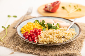 Mixed quinoa porridge, sweet corn and small sausages on white wooden, side view, selective focus.