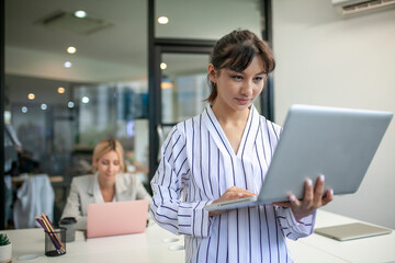 Portrait of beautiful businesswoman working with laptop at the office, female worker using computer in workplace.