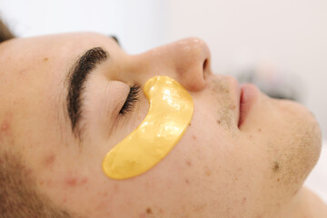 Naklejka premium Handsome man with golden patch under eyes. Beauty studio. Spa salon. Close-up. Pimples and blackheads on the skin. Acne