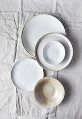 An arrangement of ceramics in natural tones on linen cloth. Top view