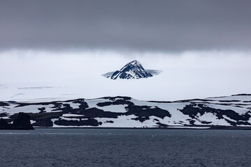 A Nunatak mountain peak on King George Island in Antarctica rises above the snow and glaciers that surround its base © Rob Schultz